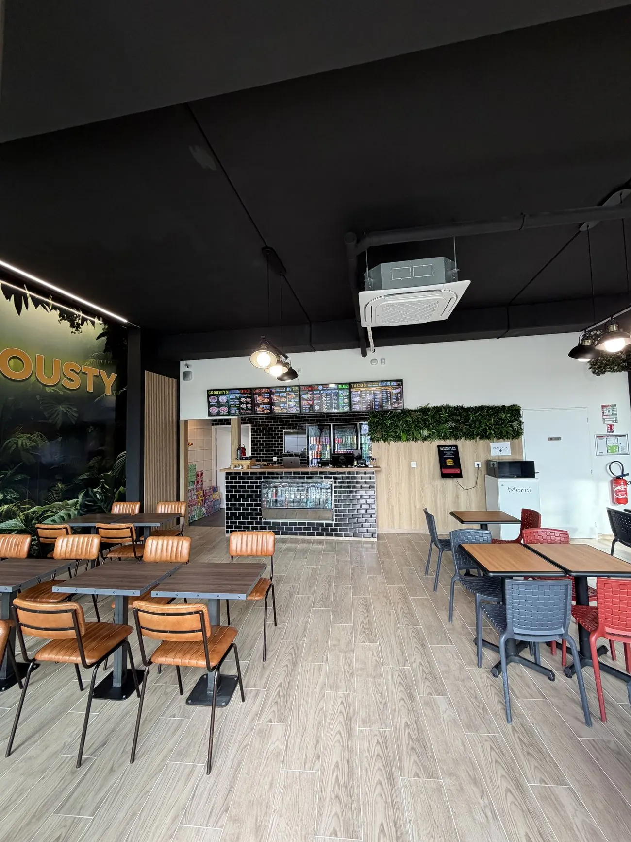 La salle de Crousty Naan à Bruges : comptoir, mur végétal et chaises en cuir camel